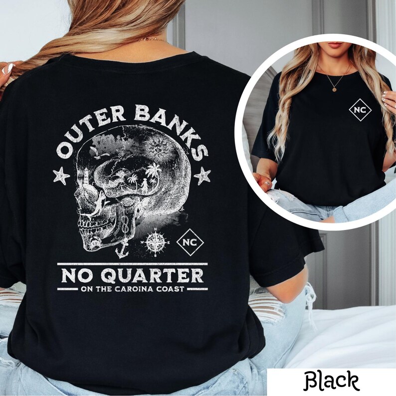 May include: Black t-shirt with a white graphic of a skull with a compass and anchor. The text "Outer Banks No Quarter - On the Carolina Coast" is printed on the shirt. The shirt also has a small white square with the letters "NC" on the back.