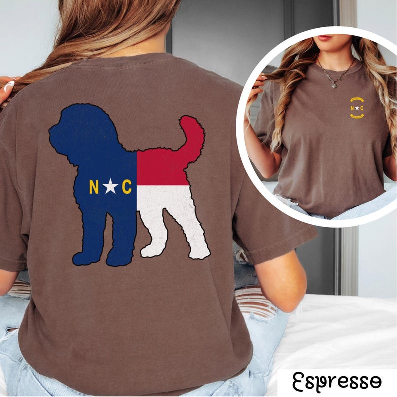 May include: A brown t-shirt with a silhouette of a dog with the North Carolina state flag design on the back. The front of the shirt has a small embroidered design of the North Carolina state flag.