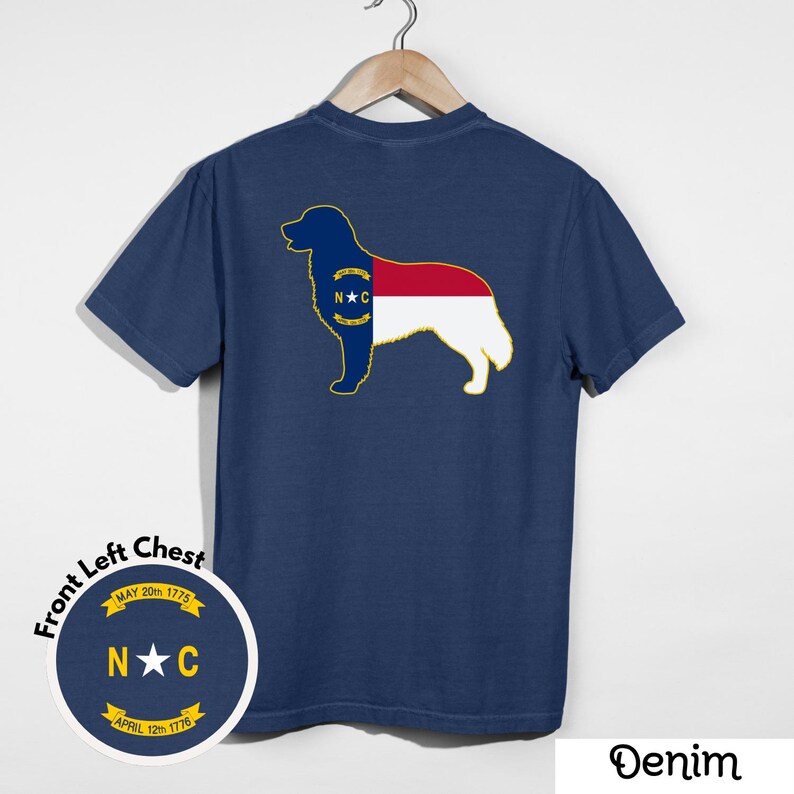 Puede incluir: Camiseta azul marino con la silueta de un perro y el dise&ntilde;o de la bandera del estado de Carolina del Norte. La camiseta tiene un emblema redondo en el pecho izquierdo con el texto "N*C" y las fechas "May 20th 1775" y "April 12th 1776". La palabra "Denim" est&aacute; en la parte inferior.