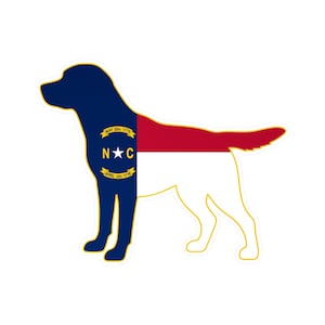 May include: A sticker in the shape of a dog, featuring the North Carolina state flag design. The dog's head and front are navy blue, with a gold emblem. The body is divided into red and white sections.