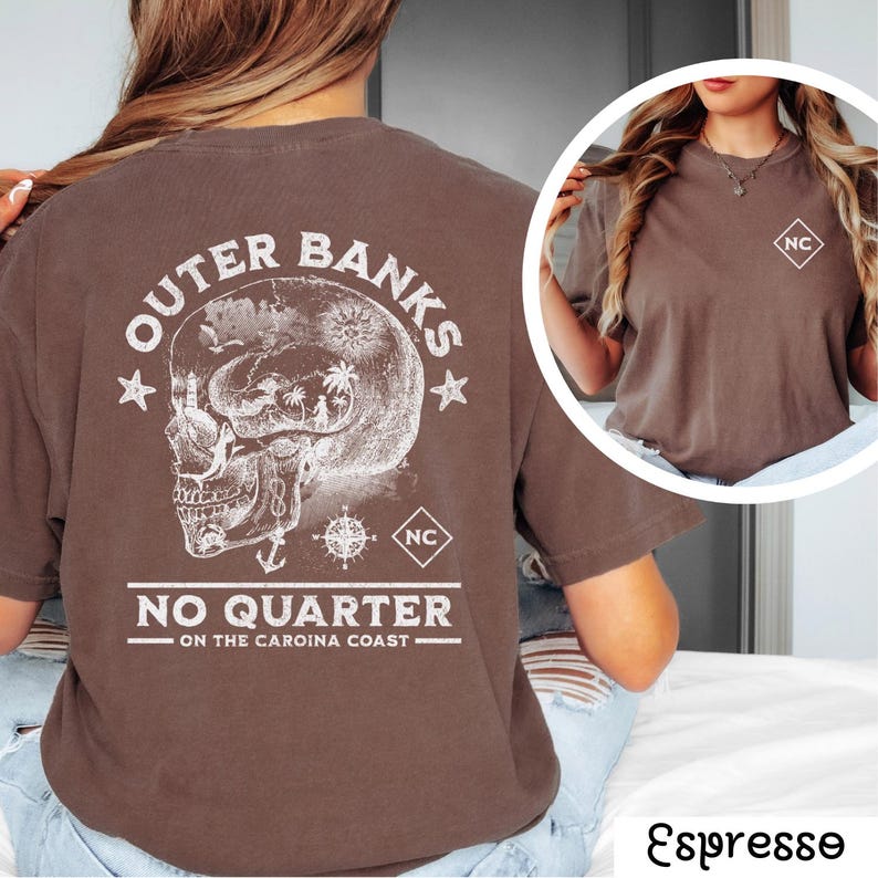 May include: Brown t-shirt with a white graphic of a skull with a compass and the text "Outer Banks No Quarter - On the Carolina Coast" and "NC" in a square.