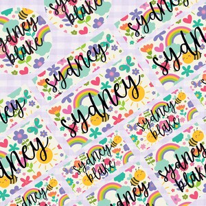 May include: A collection of colorful labels and stickers featuring the name "Sydney" in a stylish script font. The designs include rainbows, bees, flowers, butterflies, and the name "Sydney Blake". The background is a light purple checkered pattern.