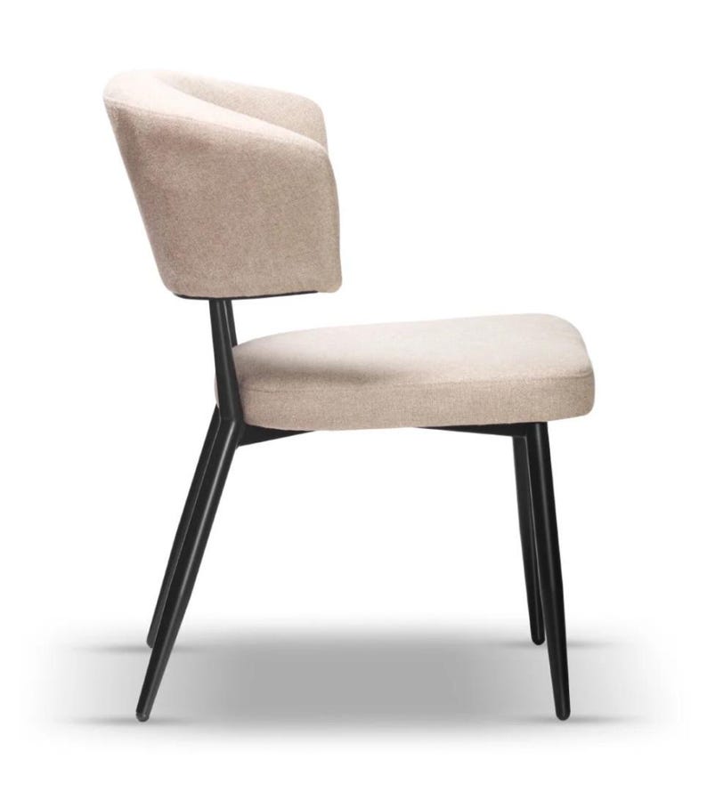 May include: A beige upholstered dining chair with a curved back and black metal legs.