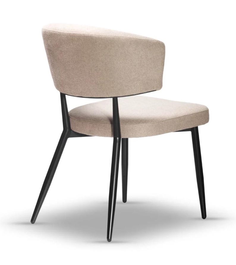 May include: A beige upholstered chair with a curved back and black metal legs. The chair has a simple, modern design.