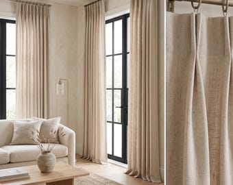 Pode incluir: Cortinas cor de areia que vão até ao chão com pregas, suspensas por um varão metálico com argolas circulares. O tecido tem uma textura visível e cai em pregas verticais sobre as grandes portas envidraçadas.