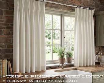 May include: Off-white triple pinch pleated linen curtains hanging on a metal rod. The text reads: TRIPLE PINCH PLEATED LINEN, HEAVY WEIGHT FABRIC, CUSTOM WIDTH & LENGTH, OPTIONAL BLACKOUT LINING. These curtains feature a structured header.