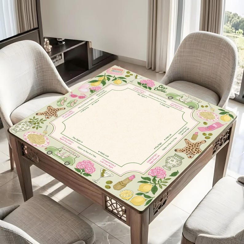 Puede incluir: Un tapete de mahjong cuadrado con un centro color crema que incluye instrucciones de juego y un borde decorado con ilustraciones de limones, hortensias rosas, coches antiguos verdes, estrellas de mar, platos de pasta, pintalabios y el texto Ciao Bella.