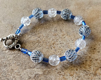 May include: A blue and silver bracelet with clear crystal beads and wire-wrapped beads. The bracelet has a silver clasp.