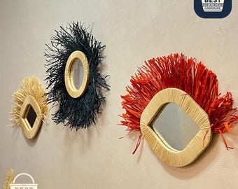 May include: Three decorative wall mirrors with natural woven frames and textured fringe in black, red, and beige. The mirrors have unique shapes and are handmade.