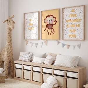 Peut inclure: Une chambre d'enfant avec une girafe en osier, trois cadres avec du texte français et une illustration de singe, et un banc de rangement avec des bacs blancs. Des coussins et une guirlande décorent la pièce.