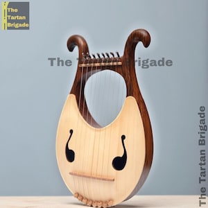 May include: A wooden lyre with a light-coloured soundboard and dark brown curved arms. The instrument has strings and decorative sound holes. The text "The Tartan Brigade" is visible in the image.