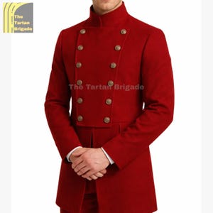 May include: A red double-breasted coat with gold-colored buttons. The coat has a high collar and a tailored fit. The text "The Tartan Brigade" is visible on the coat. The coat is a formal style.