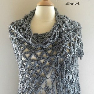 May include: A gray crocheted shawl displayed on a mannequin. The shawl features a floral pattern and fringe. Text on the image reads "Pattern" and "Petals in the Wind Shawl".