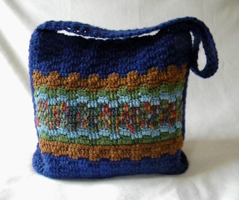 May include: A blue crocheted shoulder bag with a brown, green, and blue patterned stripe.