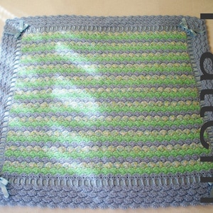 May include: A crocheted baby blanket with a blue and green striped pattern. The blanket has a crocheted border and blue ribbon ties.