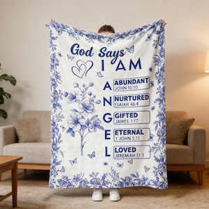 May include: A white blanket with a blue floral design and the words "God Says I AM" in navy blue. The blanket includes the words "Abundant," "Nurtured," "Gifted," "Eternal," and "Loved."