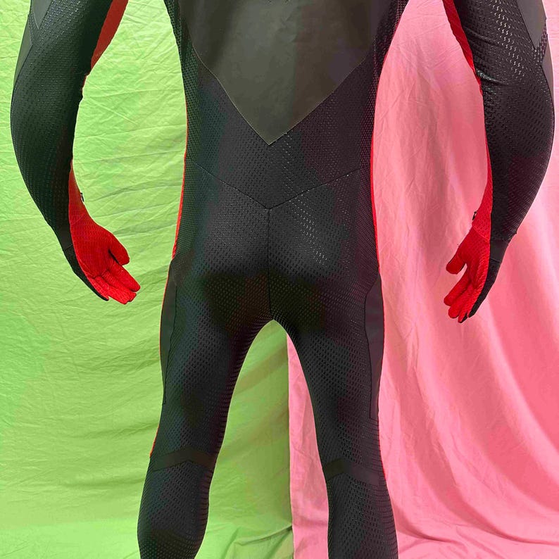 May include: Black and red athletic bodysuit. The suit has a textured, breathable fabric with red accents on the arms and legs. The gloves are red. The suit has a sleek, form-fitting design.