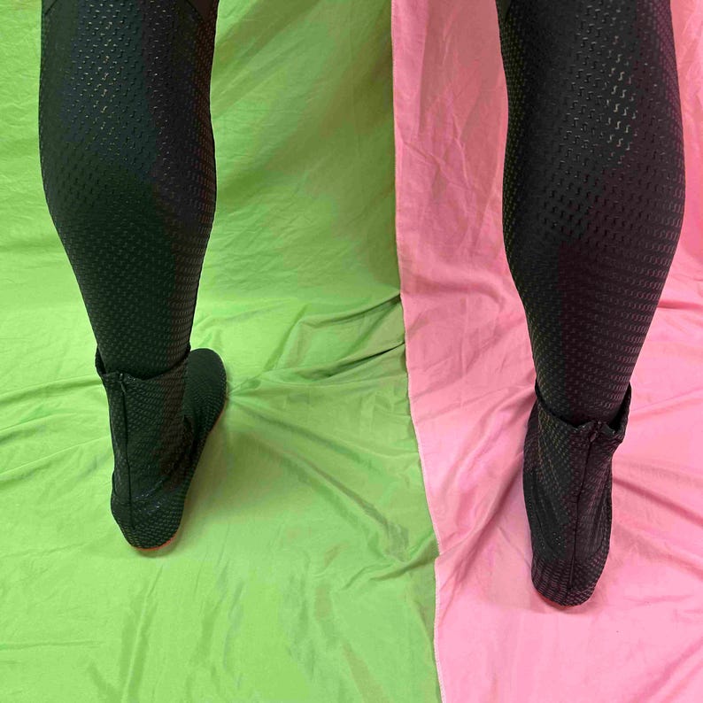 May include: Black textured leggings and ankle boots with a zip. The leggings feature a repeating pattern, displayed against a green and pink backdrop.
