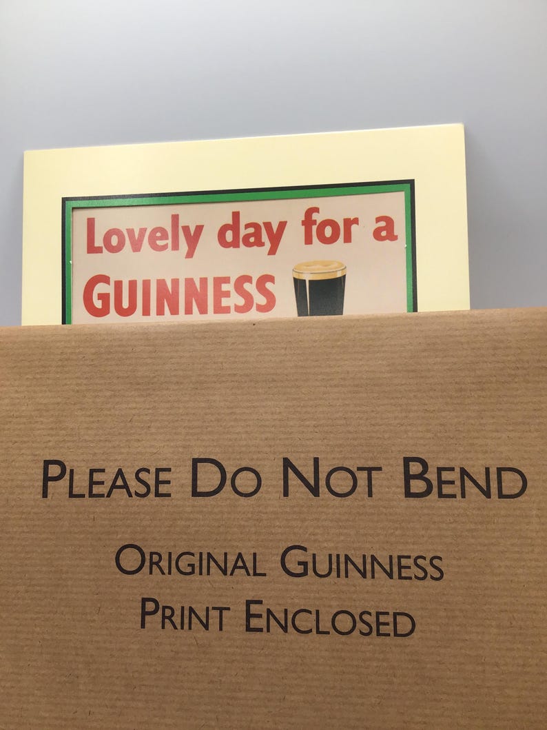 Puede incluir: Una impresi&oacute;n enmarcada con el texto "Lovely day for a GUINNESS" y una imagen de una pinta de Guinness. La impresi&oacute;n est&aacute; en un marco color crema, y el embalaje dice "PLEASE Do Not BEND" y "ORIGINAL GUINNESS PRINT ENCLOSED."