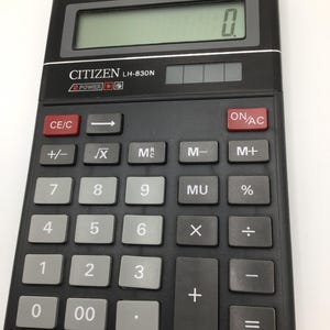 Peut inclure: Une calculatrice noire Citizen LH-830N avec des boutons gris et un écran numérique vert affichant "0". La calculatrice a un affichage à 10 chiffres et des boutons pour les fonctions mathématiques de base.
