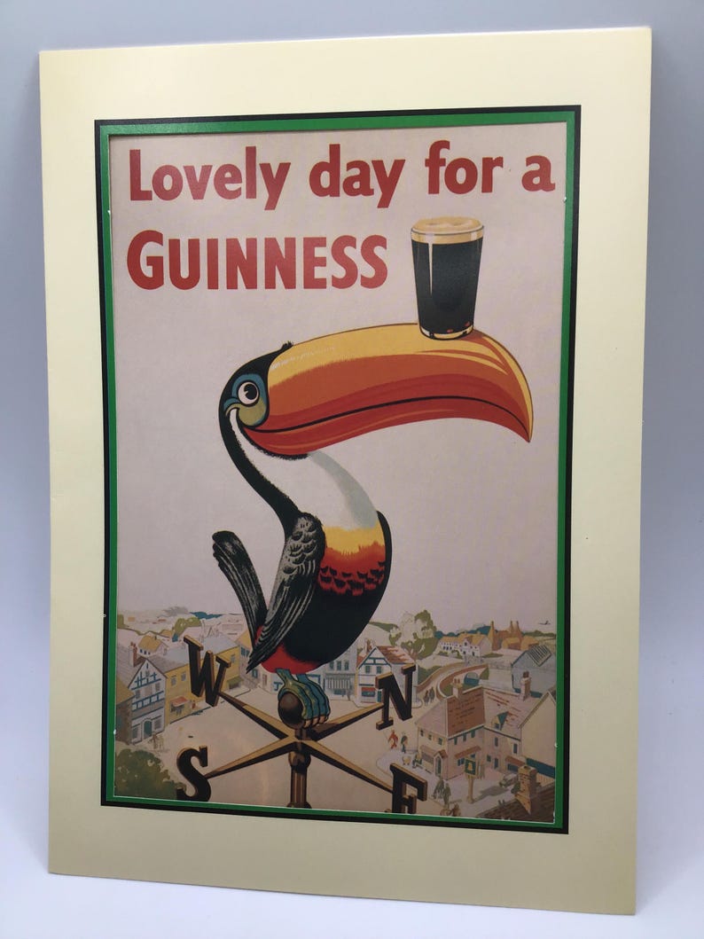 Puede incluir: Impresi&oacute;n enmarcada con un tuc&aacute;n sosteniendo una pinta de Guinness. El texto dice "Lovely day for a Guinness". La imagen incluye una escena de pueblo y una veleta. El marco es verde.