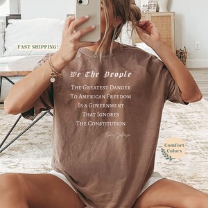 Puede incluir: Camiseta marr&oacute;n con el texto "We The People" y una cita de Thomas Jefferson. La cita dice: "El mayor peligro para la libertad estadounidense es un gobierno que ignora la Constituci&oacute;n."