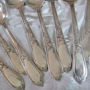 May include: Set of eight silver spoons with ornate floral designs on the handles.