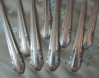May include: Set of eight silver-plated dinner forks with ornate designs. The forks have a classic, vintage style.