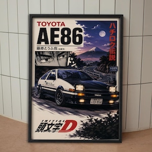 May include: A framed poster featuring a black and white Toyota AE86 Trueno car driving on a mountain road at night. The artwork includes a view of Mount Fuji, a moonlit sky, a close-up of a person's eyes, and the text Toyota AE86 and Initial D.