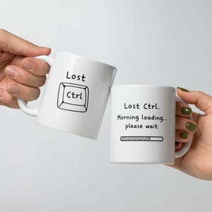 Puede incluir: Dos tazas de cerámica blancas con texto negro. Una taza dice "Lost Ctrl" con un gráfico de tecla Ctrl. La otra dice "Lost Ctrl. Morning loading... please wait" con un gráfico de barra de carga. Ambas tazas tienen asas blancas.