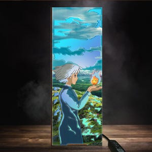 May include: A rectangular decorative panel featuring an anime-style illustration. The artwork depicts a character with white hair and blue clothing holding a small, orange flame. The background shows a landscape with mountains, trees, and a blue sky with clouds.