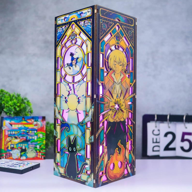 May include: A tall, rectangular wooden lamp featuring intricate, multi-colored stained glass-style panels. One side displays a blonde character holding a glowing light, while the other side depicts a black cat and a small figure in a blue hat.