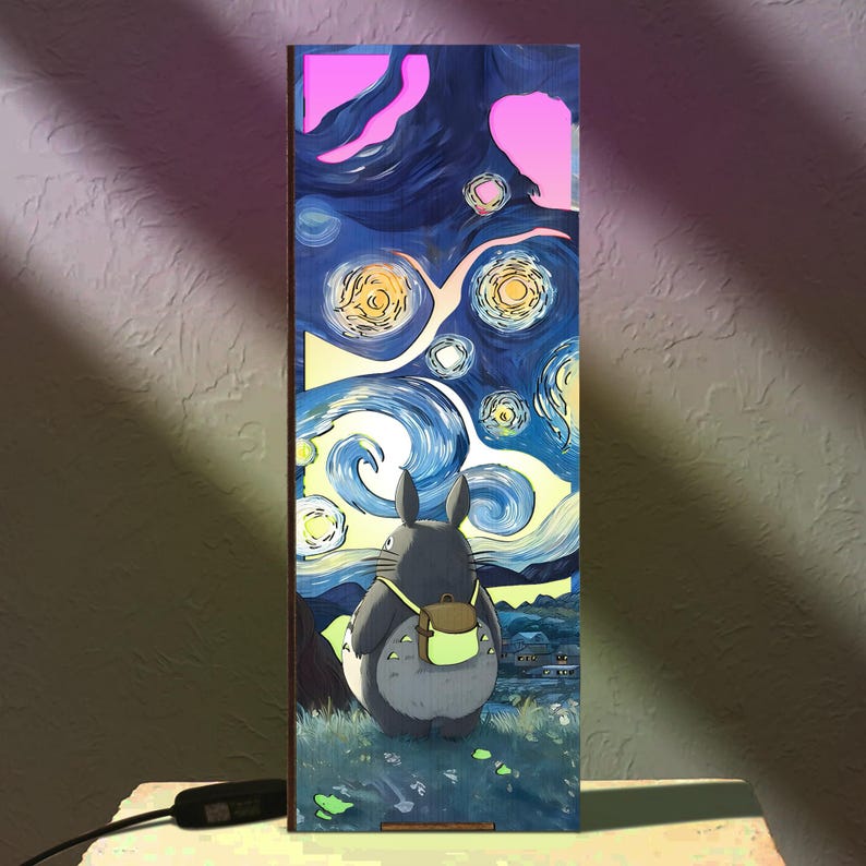 Może przedstawiać: Prostokątna drewniana lampa przedstawiająca Totoro patrzącego na gwiaździste niebo. Grafika jest w stylu "Gwieździstej nocy" Van Gogha. Lampa ma czarny przew&oacute;d zasilający i włącznik.