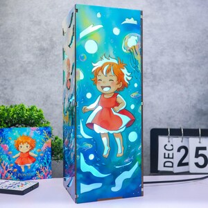 May include: A rectangular wooden lamp featuring a vibrant underwater scene with a cartoon character in a red dress swimming among bubbles, jellyfish, and fish. The design is illuminated with blue tones, and the character has orange hair.