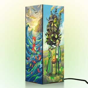 May include: A rectangular table lamp featuring vibrant anime-style illustrations on its sides. One side depicts a character running through ocean waves with orange fish, while the other shows a large mechanical castle and two figures with a fire spirit.