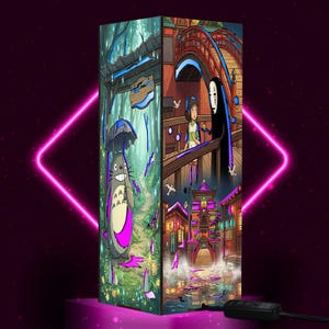 May include: A rectangular lamp featuring vibrant anime-style illustrations on its panels. One side shows a grey creature with an umbrella in a forest, while other panels depict a character with a white mask on a bridge and a glowing building scene.