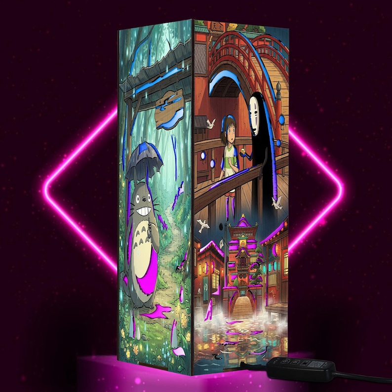 May include: A rectangular lamp featuring vibrant anime-style illustrations on its panels. One side shows a grey creature with an umbrella in a forest, while other panels depict a character with a white mask on a bridge and a glowing building scene.