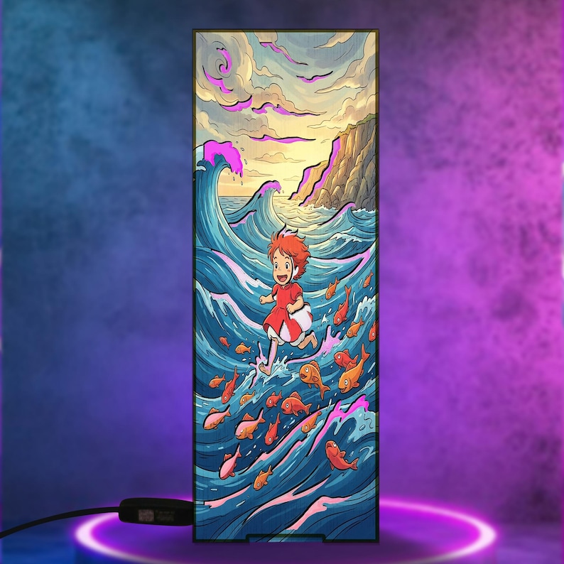 May include: A rectangular LED light panel featuring a colorful illustration of a small child with red hair running across blue ocean waves surrounded by orange fish, with a rocky cliffside in the background under a cloudy sky, connected by a black cord.