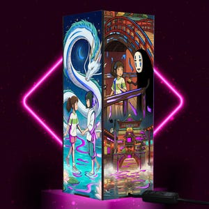 Puede incluir: Una l&aacute;mpara decorativa con ilustraciones de la pel&iacute;cula de animaci&oacute;n El viaje de Chihiro. La l&aacute;mpara tiene forma rectangular y muestra ilustraciones coloridas de personajes y escenas de la pel&iacute;cula. La l&aacute;mpara tiene un cable de alimentaci&oacute;n negro y un bot&oacute;n de encendido negro.