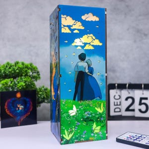 May include: A rectangular wooden lamp featuring a blue sky design with clouds and stars. The lamp depicts a couple standing on a grassy field with butterflies. The lamp has a decorative design on the sides and is lit from within.