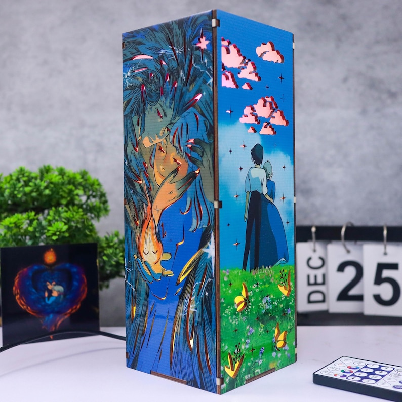 May include: A rectangular wooden lamp with a colorful anime-style illustration. The artwork features figures in a field with butterflies, clouds, and a couple. The lamp has a blue and green color scheme, with a remote control visible.
