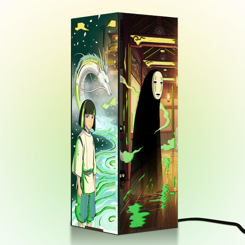 Puede incluir: L&aacute;mpara rectangular con ilustraciones de estilo anime. Un lado representa a un joven y un drag&oacute;n blanco cerca de un r&iacute;o. El otro lado muestra una figura con capa y m&aacute;scara negras. La l&aacute;mpara tiene un cable de alimentaci&oacute;n negro.