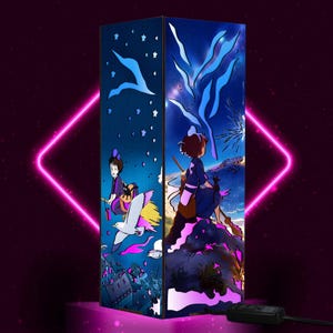 May include: A rectangular lamp featuring anime-style illustrations. One side depicts a girl on a broom with a bird, the other shows a girl sitting on a rock. The lamp has a dark blue background with stars and other design elements.