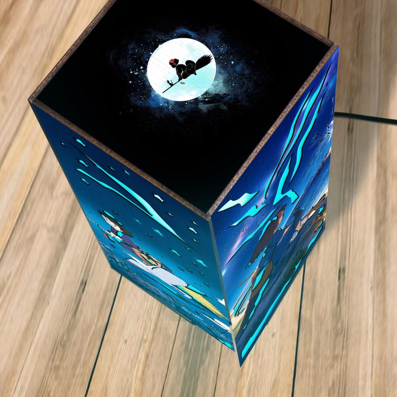 May include: A decorative lamp with a night sky theme. The top of the lamp features a full moon with a witch silhouette. The sides of the lamp are decorated with a blue and white illustration of a night scene.