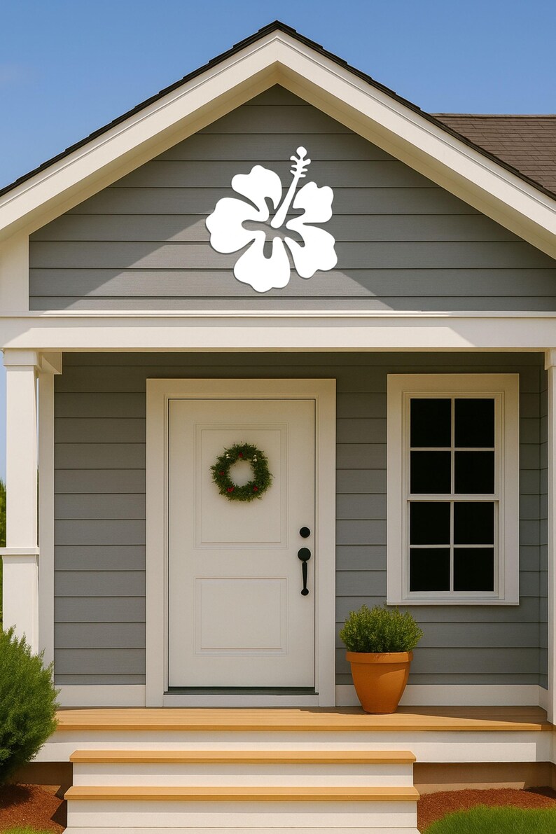 Puede incluir: Una decoraci&oacute;n de flor de hibisco blanca montada en el revestimiento gris de una casa. La casa tiene una puerta blanca con una corona, una ventana y una peque&ntilde;a planta en maceta. Los escalones y los adornos son de madera clara.