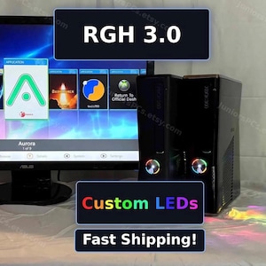 May include: A black Xbox 360 console featuring custom LED lights on the power button, displayed next to an ASUS monitor showing the Aurora dashboard interface with the text RGH 3.0, Custom LEDs, and Fast Shipping! visible in the image overlay.