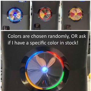 K&ouml;nnte beinhalten: Ein schwarzes elektronisches Ger&auml;t mit einem runden Knopf in Metallic-Optik und einer leuchtenden LED. Das Bild zeigt verschiedene Lichtfarben, darunter Blau, Orange, Gr&uuml;n und Rot. Text: Colors are chosen randomly, OR ask if I have a specific color in stock! See description for more info!!!