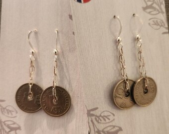 May include: Silver dangle earrings featuring vintage Norwegian coins. Each earring has a chain and a coin pendant. The earrings are displayed on a white card with a Norwegian flag sticker.