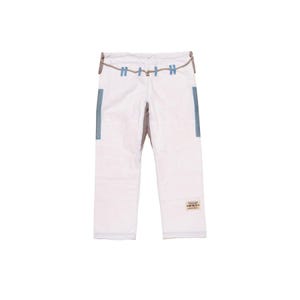May include: White martial arts pants featuring a drawstring waist with light blue loops, light blue side panels on the upper thighs, and a small rectangular patch with text on the lower right leg. The pants have a structured, durable fabric design.