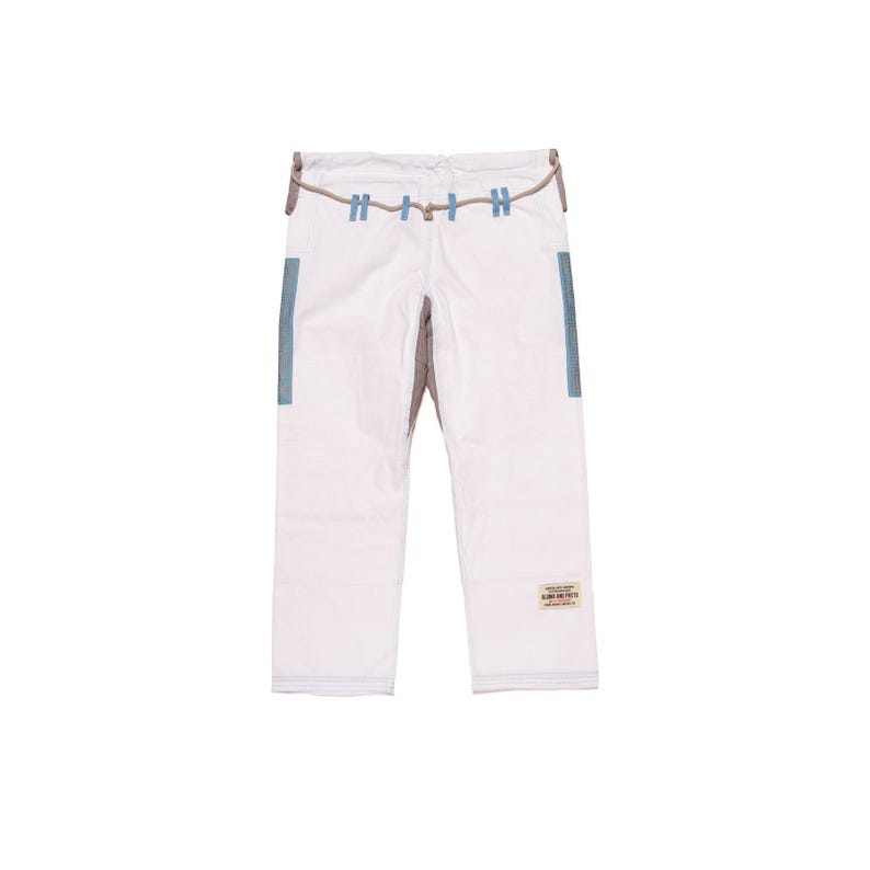 May include: White martial arts pants featuring a drawstring waist with light blue loops, light blue side panels on the upper thighs, and a small rectangular patch with text on the lower right leg. The pants have a structured, durable fabric design.